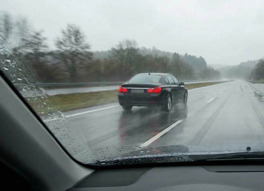 Zwarte auto rijdt veilig door op de snelweg tijdens regen dankzij runflat banden